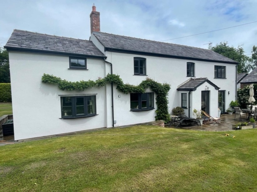 Long white rendered cottage with slate roof and dark window frames