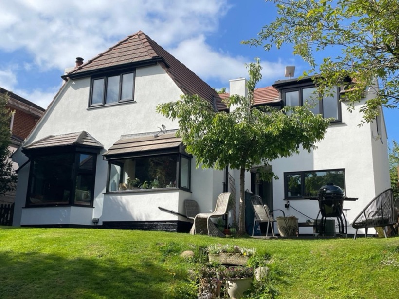 A detached house freshly finished in white render, photographed from the garden